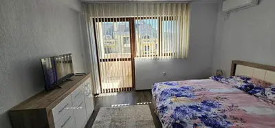 a bedroom with a bed and a television and a window at Д и В 3 - D & V 3 Apartment in Sandanski