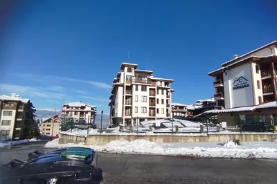 a snowmobile parked in a parking lot in front of buildings at 2BR mountain view, SPA, parking, ski piste in Bansko