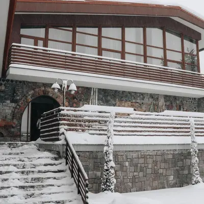 a building with snow covered steps and a building with a window at Хижа Марциганица in Asenovgrad