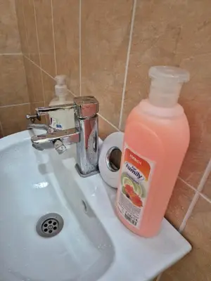 a bottle of orange juice sitting on a bathroom sink at Private stay place in Sofia