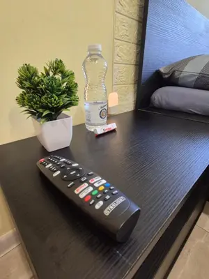 a remote control sitting on a table with a bottle of water at Private stay place in Sofia