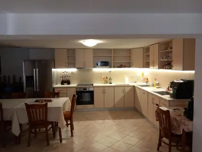 a kitchen with white cabinets and a table with a dining room at Къща за гости МИЧЕВИ in Shipkovo