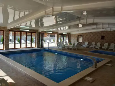 a large swimming pool in a building with a pool at Къща за гости МИЧЕВИ in Shipkovo