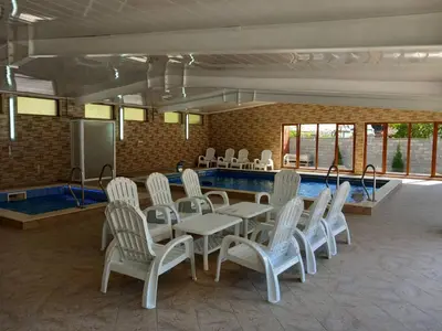 a dining room with a table and chairs and a pool at Къща за гости МИЧЕВИ in Shipkovo