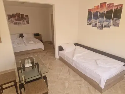 a bedroom with two beds and a glass table at Къща за гости МИЧЕВИ in Shipkovo