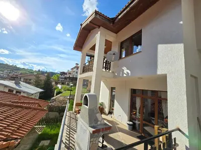 a white house with a balcony with a view at Вила 5 - Планински перли in Stoykite