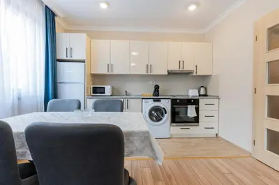 a kitchen with a dining table and a kitchen with white cabinets at Bissera premium apartments in Sofia