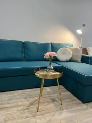 a blue couch with a vase of flowers on a table at Nomadic Travelers Apartment in Sofia