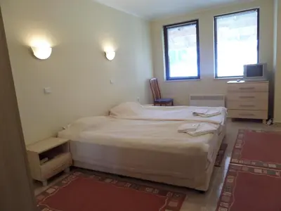 a bedroom with two beds and a tv and two windows at Apartment in Complex Monastery 1 in Pamporovo