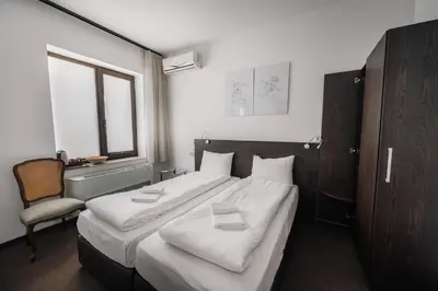 a bedroom with a large bed with white sheets and a chair at Лондонъ - къща за гости / London - guest house in Kyustendil