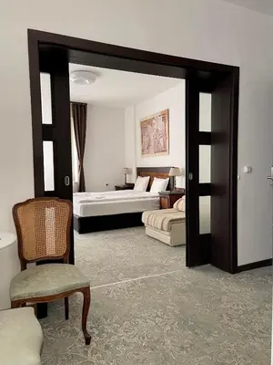 a room with two beds and a chair and a mirror at Лондонъ - къща за гости / London - guest house in Kyustendil