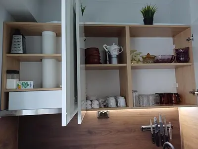 a kitchen cabinet filled with lots of dishes at Maya's Airport Apartment in Sofia