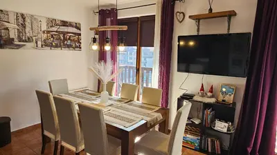 a dining room table with chairs and a television at Bansko Prespa Ski Penthouse in Bansko