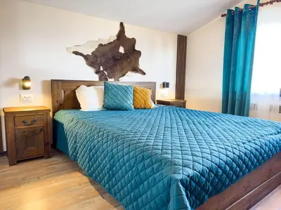 a bedroom with a bed with a blue comforter at Private cozy at Alpin Lodge Studio + SPA Complex in Bansko