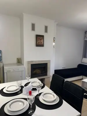 a dining room table with plates and wine glasses on it at Grand Monastery Pamporovo Luxury Apartment in Pamporovo