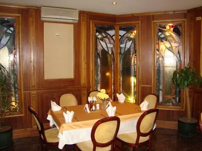 a dining room with a table and chairs and stained glass windows at Хотел-ресторант Астория in Pazardzhik