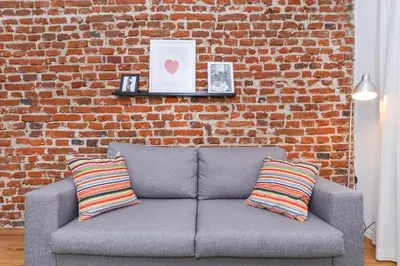 a couch against a brick wall with two striped pillows at Antim Boutique Apartments in Sofia