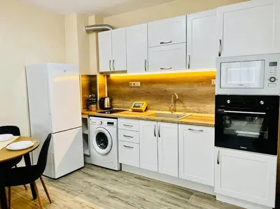 a kitchen with white cabinets and a sink and a dishwasher at Malinova Stylish Apartment in Sofia