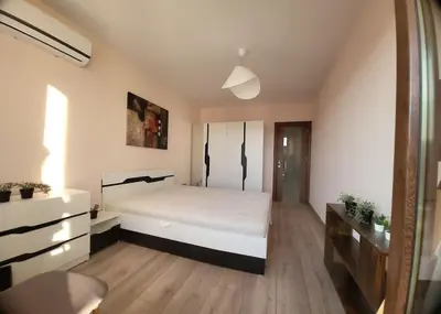 a bedroom with a large white bed and wooden floors at Stylish apartment near City, entire flat, 1 bedroom, 1 large bed in living room in Plovdiv