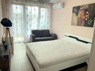 a bedroom with a bed and a chair and a window at Stylish apartment near City, entire flat, 1 bedroom, 1 large bed in living room in Plovdiv