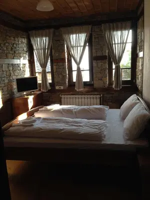 a large bed in a room with windows at Delchevata Kushta V Leshten in Leshten