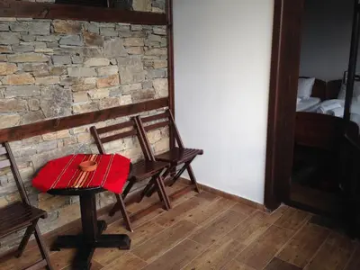a room with two chairs and a table with a red blanket at Delchevata Kushta V Leshten in Leshten