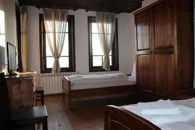 a bedroom with two beds and two windows at Delchevata Kushta V Leshten in Leshten