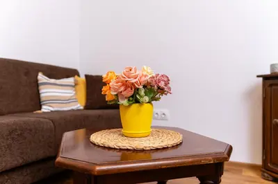 a yellow vase filled with flowers on a table at City Center Retro Chic Kapana 2-Bed Apartment in Plovdiv
