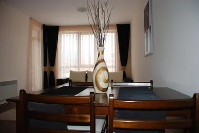 a dining room table with a vase on top of it at Едноспален апартамент Pirin Palace in Bansko