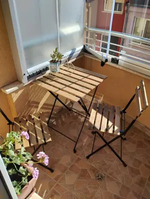 a wooden table and chairs on a balcony with flowers at Happy Apartment & Free Breakfast - Mladost in Sofia