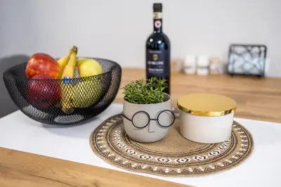 a table with a bowl of fruit and a bottle of wine at Modern 1BR Comfort in Oborishte with Private Parking in Sofia
