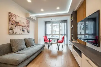 a living room with a couch and a table with red chairs at Zenith Apartment in Sofia