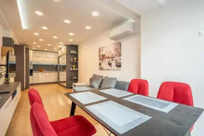 a dining room with a table and red chairs at Zenith Apartment in Sofia