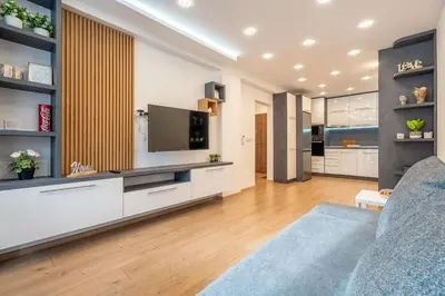a living room with a tv and a blue couch at Zenith Apartment in Sofia