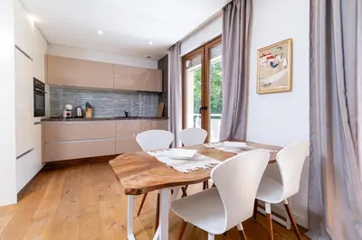 a kitchen and dining room with a wooden table and white chairs at Central 1-bedroom Apartment in Plovdiv