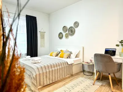 a white bedroom with a bed and a chair at Cozy Apartment near Vitosha Blvd in Sofia