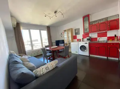 a living room with a couch and a kitchen with red cabinets at New Two Bedroom apartment with balcony in Sofia