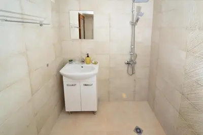 a white bathroom with a sink and a shower at Стаи за гости Ингилизовата къща in Padala