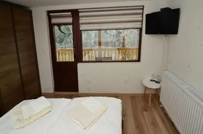 a bedroom with a bed with white sheets and a window at Стаи за гости Ингилизовата къща in Padala