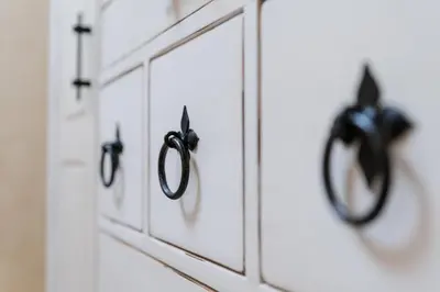 a row of white cabinets with black handles at Elegant 1-Bedroom Apartment in Plovdiv