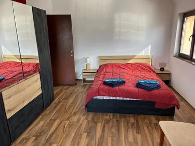 a bedroom with two beds with red sheets and wooden floors at Apartament Armada Bansko in Bansko