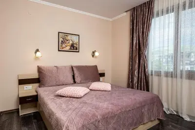 a bedroom with a bed with pink pillows and a window at Апартамент за гости ВениАн in Velingrad