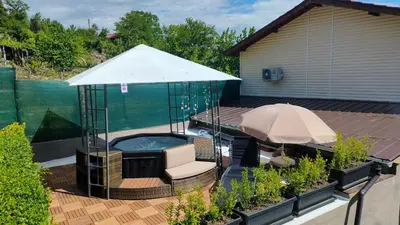 a hot tub with an umbrella next to a swimming pool at Guest House Saint George in Vukovo
