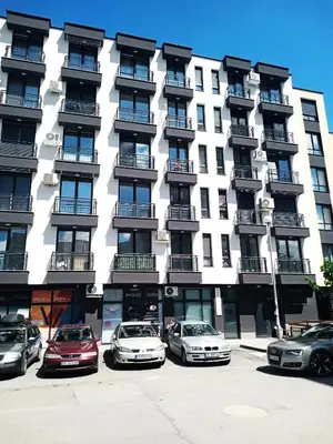 a tall white building with cars parked in front of it at Alis Savana in Sofia