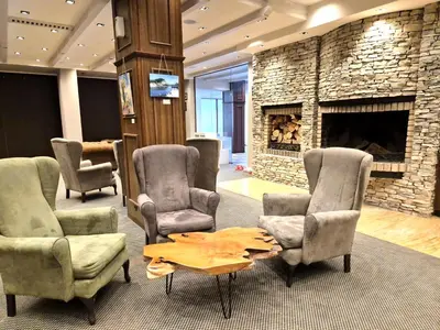 a living room with chairs and a stone fireplace at Cozy apartment in luxury SPA resort St Ivan Rilski Bansko -free wellness & parking- in Bansko