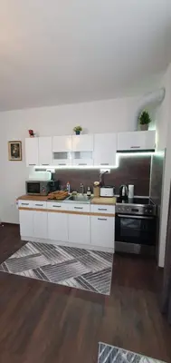 a kitchen with white cabinets and a black stove at АПАРТАМЕНТ ЮЛИЯ ДЕЛУКС II in Velingrad