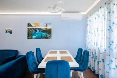 a dining room with a table and blue chairs at Feel at Home - Central 2BD Flat with Parking by Flat Mаnager in Sofia