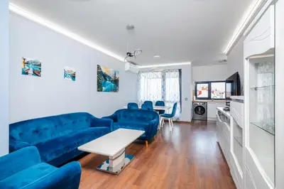 a living room with a blue couch and a table at Feel at Home - Central 2BD Flat with Parking by Flat Mаnager in Sofia