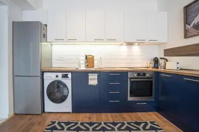 a kitchen with blue cabinets and a washing machine at Cozy Apartment Overlooking The Park in Sofia