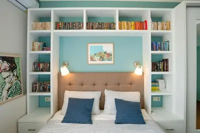 a bedroom with a bed with blue walls and bookshelves at Home in Sofia's Beating Heart in Sofia